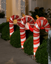 Inflatable light up candy canes holiday on a grassy area with a building in the background